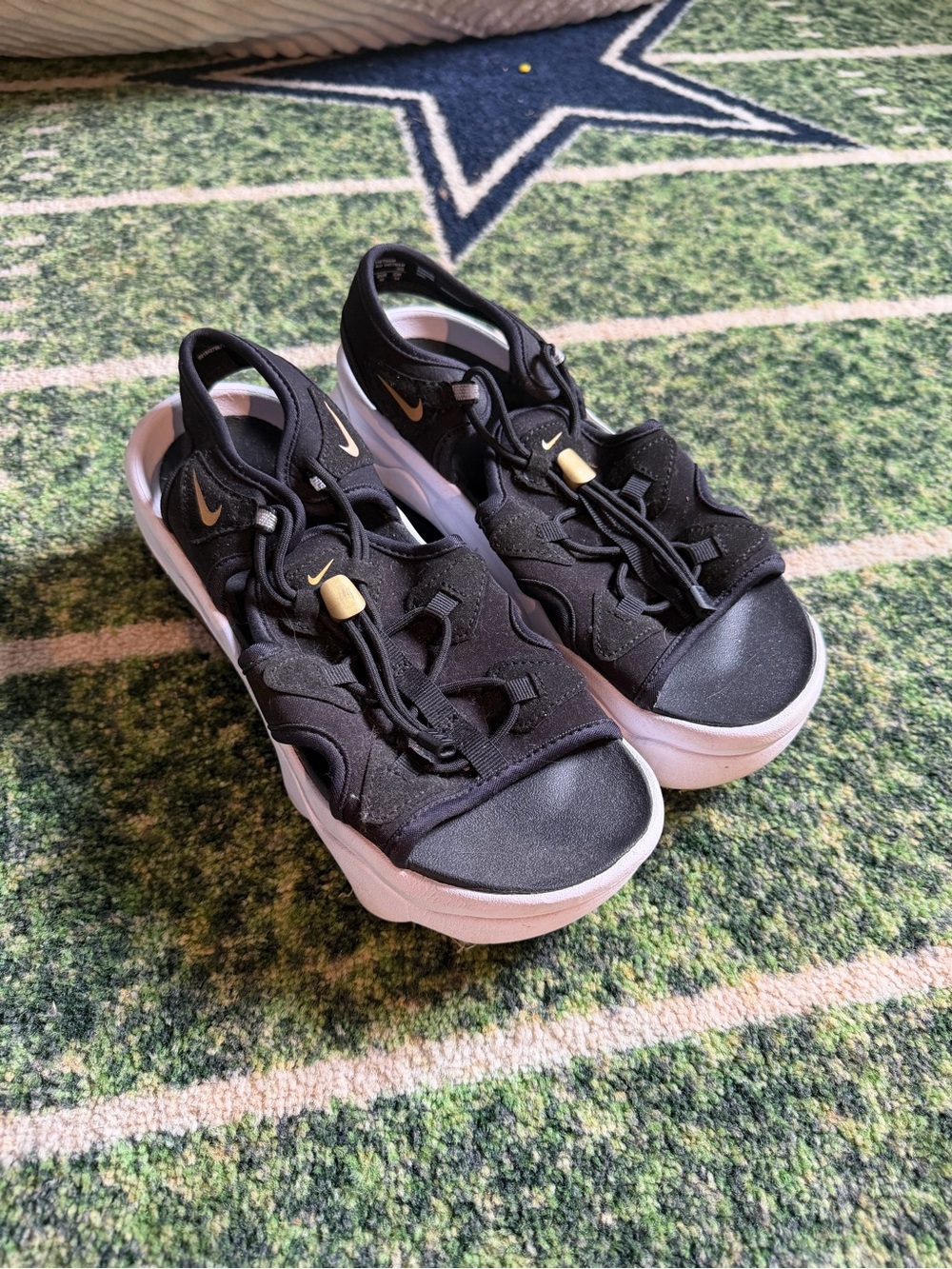 Nike Women’s Black Sandals with Gold Swoosh and White Sole